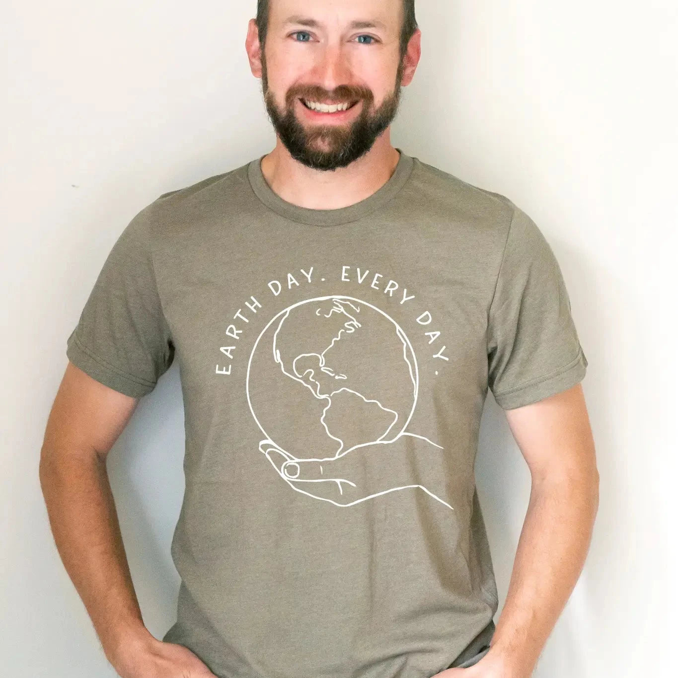 A person standing and smiling, wearing a gray graphic tee with the text 'EARTH DAY EVERY DAY' and a graphic of the Earth.