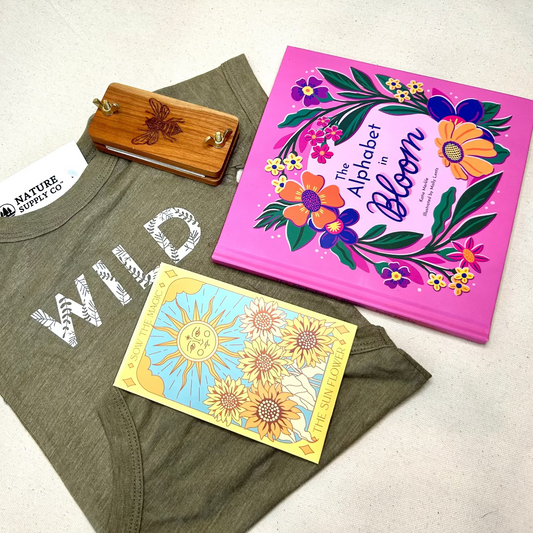 Green t-shirt with 'WILD' text, children's books, and a wooden item on a light background