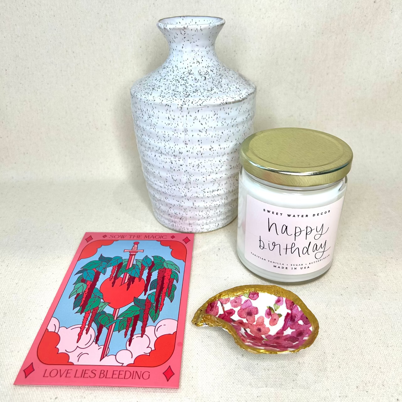 Decorative items including a candle, vase, card, and small dish on a white surface