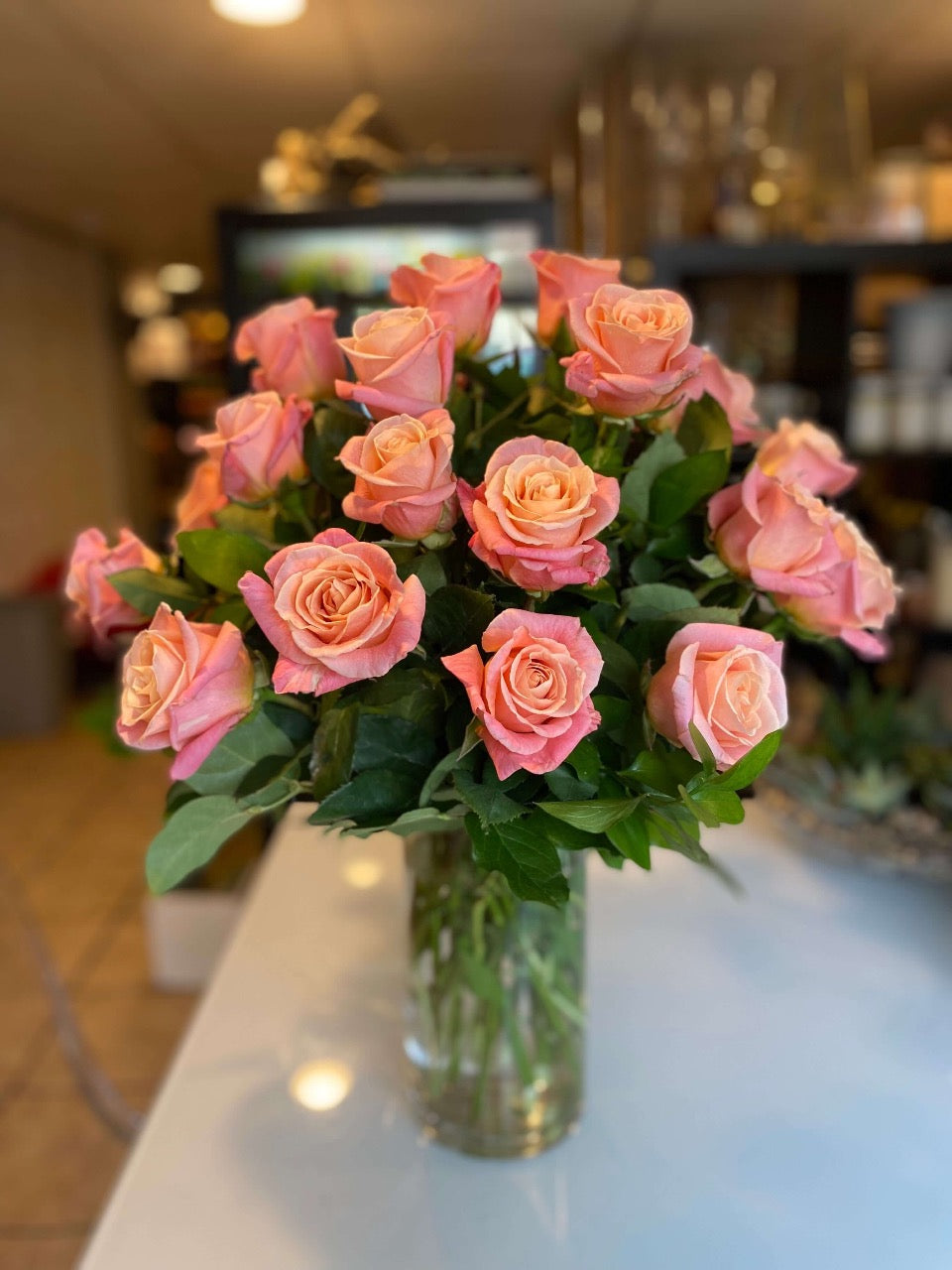 2 dozen coral pink roses in a vase