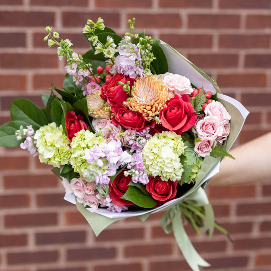 Bouquet of paper wrapped flowers against brick wall
