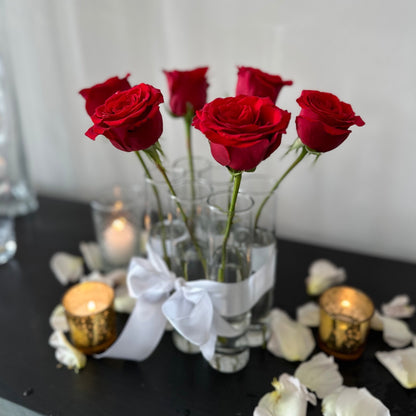 Sleek glass bud vases with red roses, grouped together as six pack tied with white ribbon