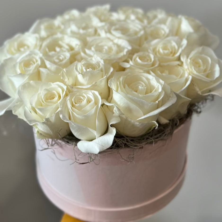 A pave design of white roses in a pink hat box.