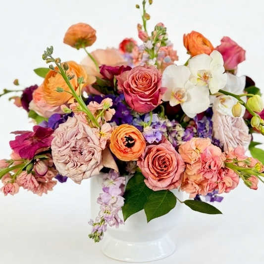 Colorful flower arrangement in a white vase on a white background