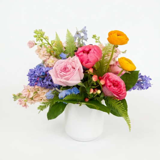 Colorful flower arrangement in a white vase on a light background