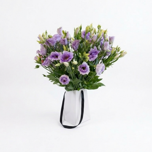 Bouquet of purple flowers in a white vase on a white background.