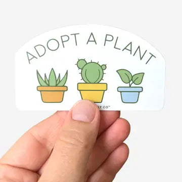 A sticker with the text 'ADOPT A PLANT' and illustrations of three different potted plants: a cactus, a succulent, and a green plant, held against a white background.