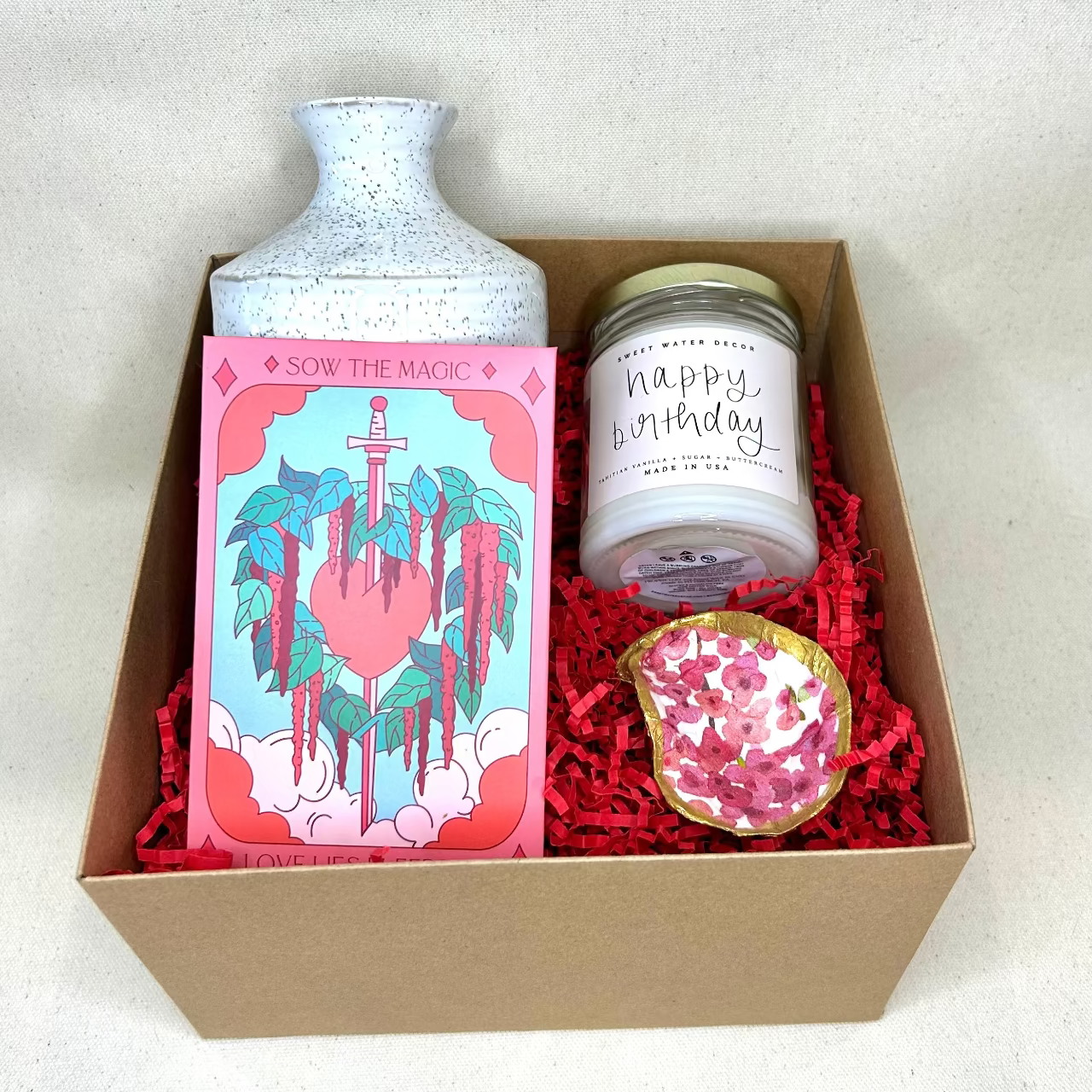 Gift box with a bottle, candle, and decorative item on a white background