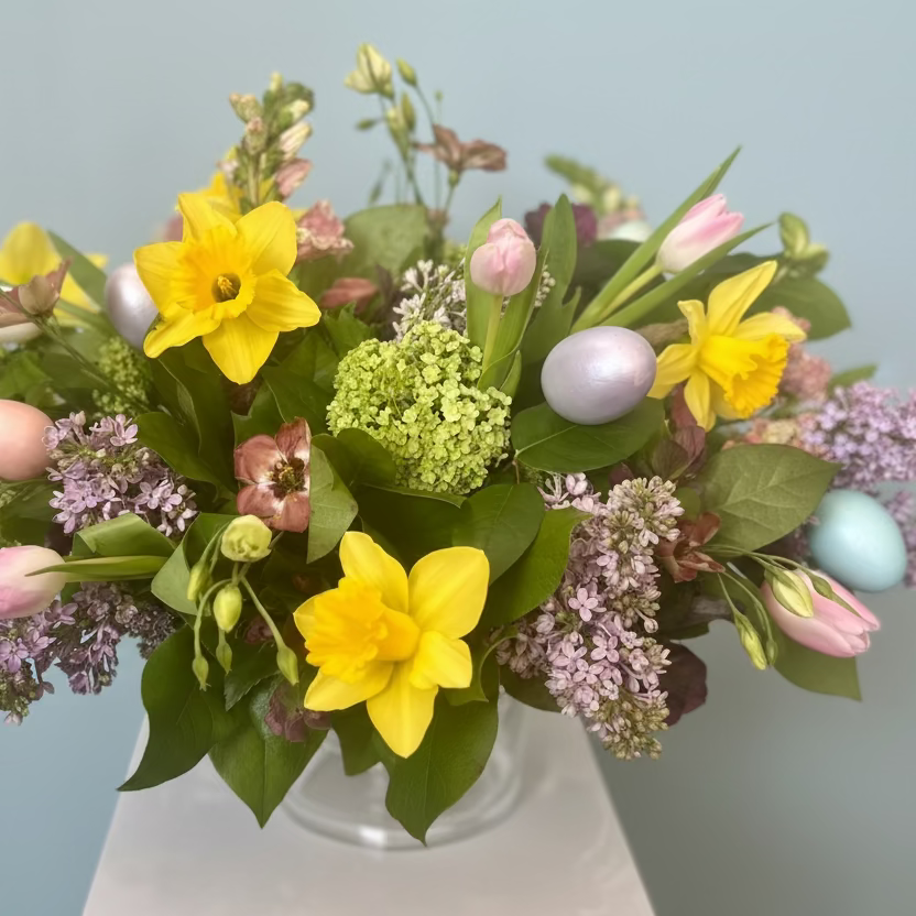 Bouquet of flowers with Easter eggs on a light blue background