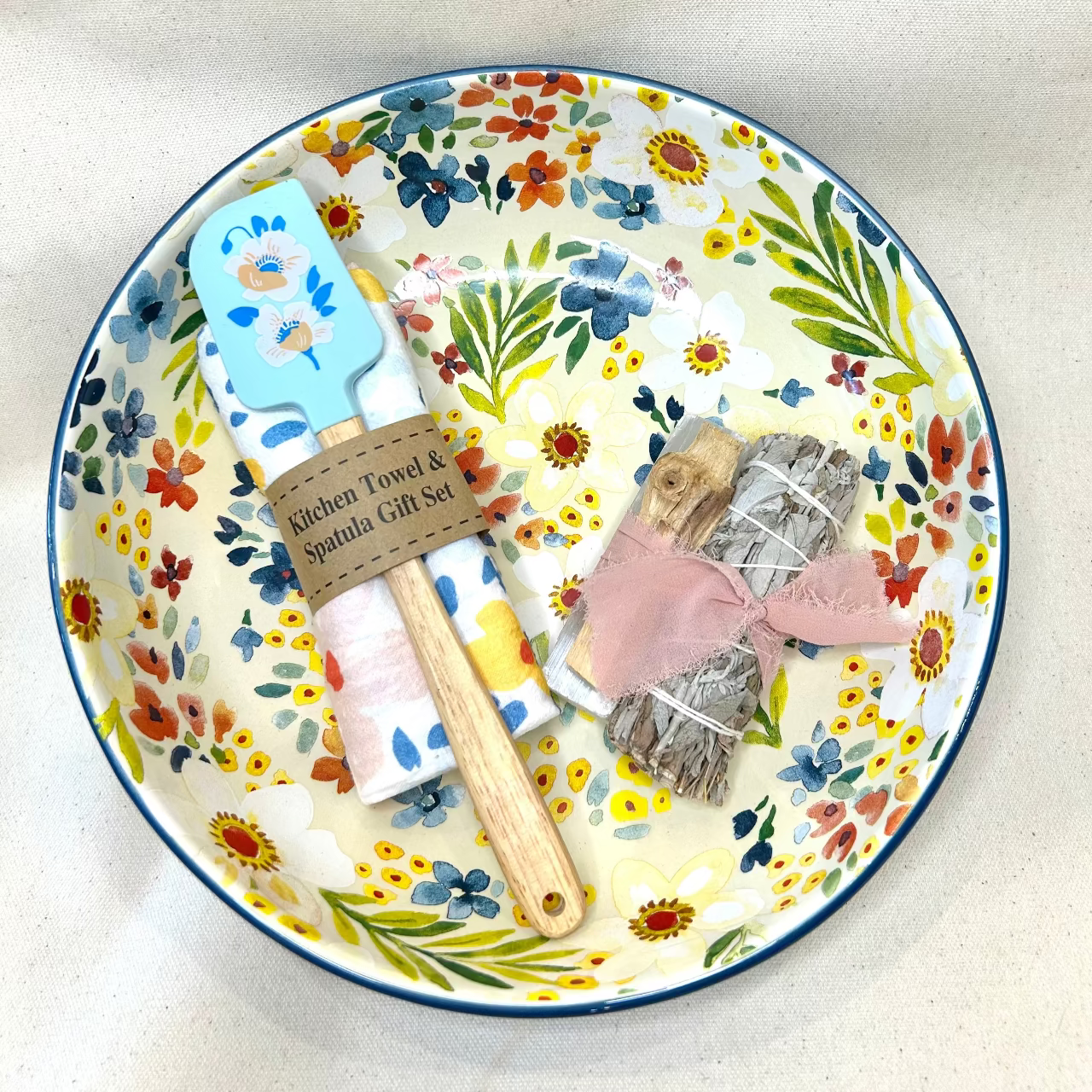 Floral-patterned plate with kitchen towel and spatula on a white background