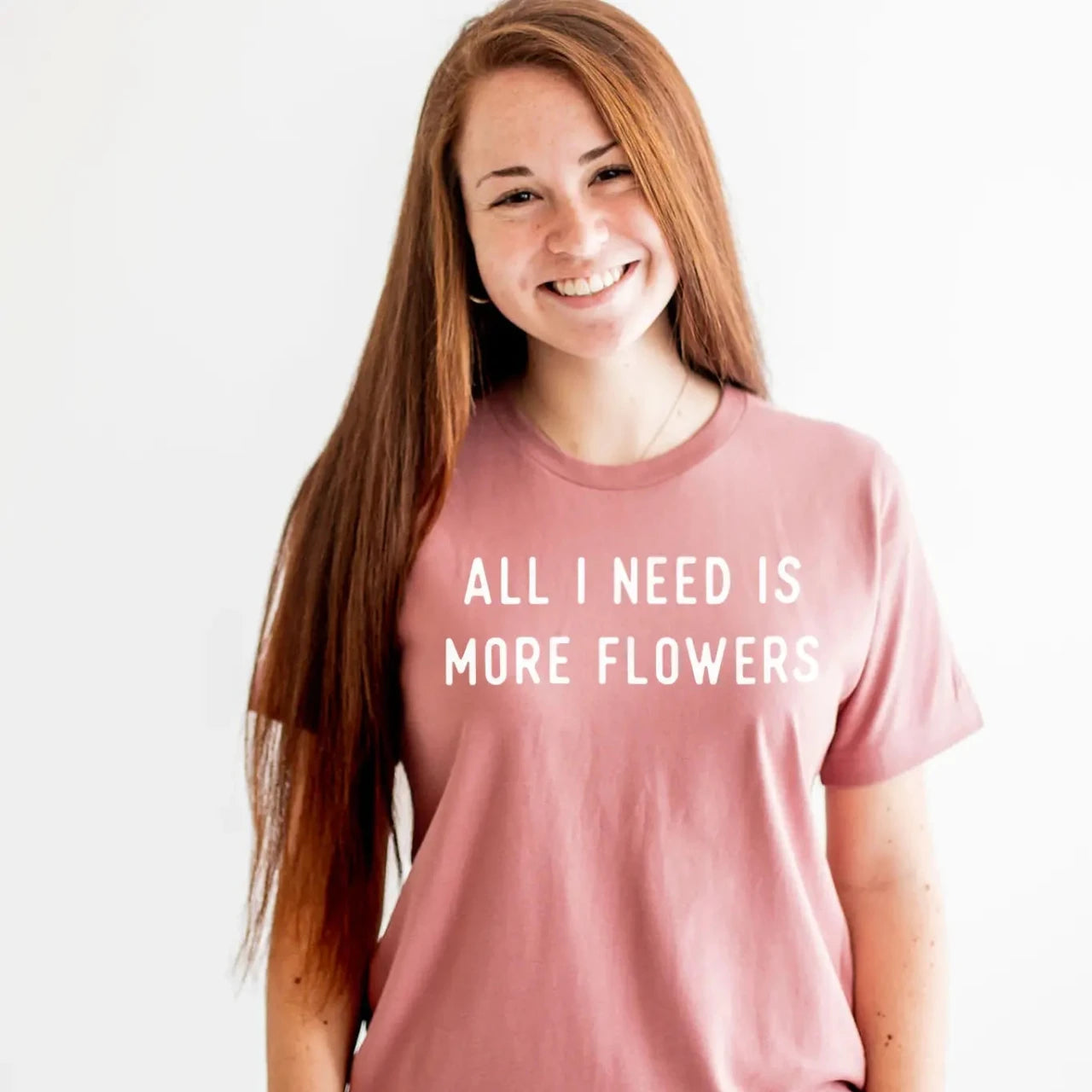Woman wearing pink t-shirt that says All I Need is More Flowers