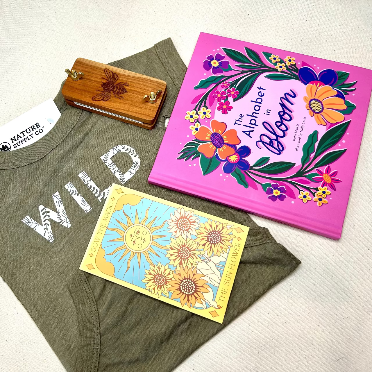 Green t-shirt with 'WILD' text, children's books, and a wooden item on a light background