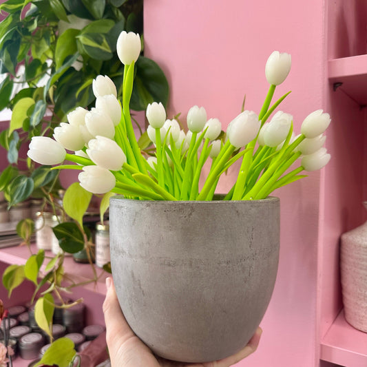 White tulip pens held by a hand against a pink background