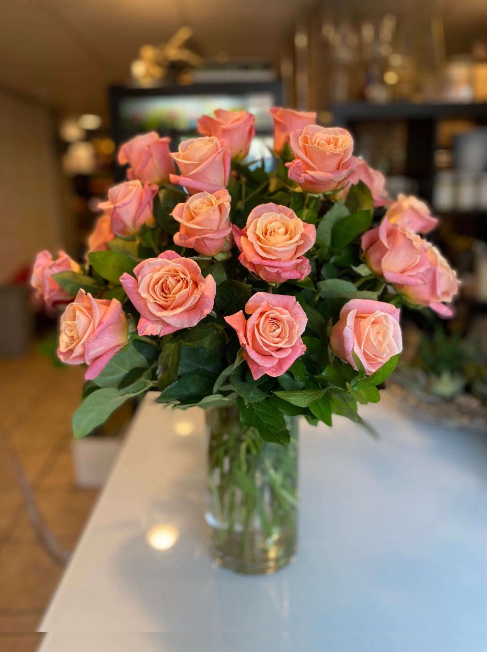 2 dozen coral pink roses in a vase