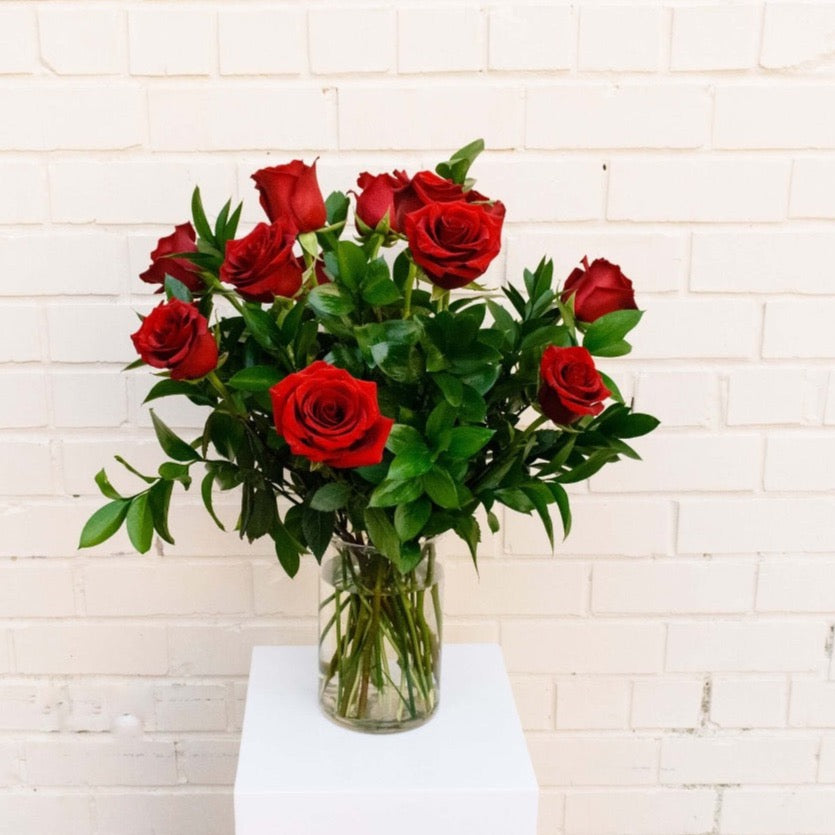 One dozen romantic red roses, accented with seasonal greens, makes for a classic expression of love.