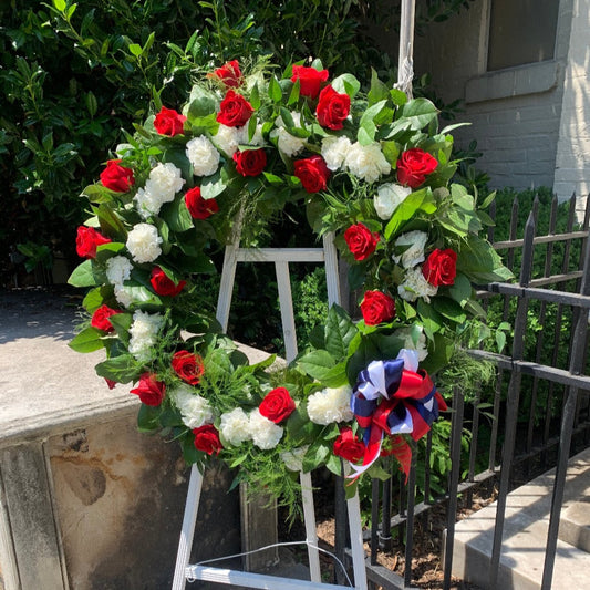 Patriotic wreath of red roses and white carnations finished with red, white and blue ribbon